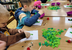 Dzieci wyklejają choinki.