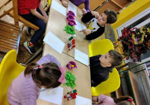 Dzieci wyklejają choinki.