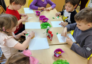 Dzieci wyklejają choinki.