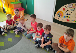 Dzieci siedzą na dywanie.