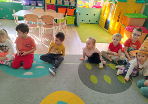 Dzieci siedzą na dywanie.