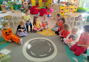 Dzieci siedzą na dywanie.