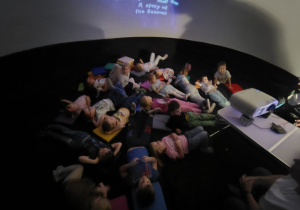 Dzieci leżą i ogladają film.