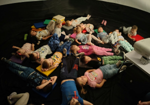 Dzieci leżą i ogladają film.