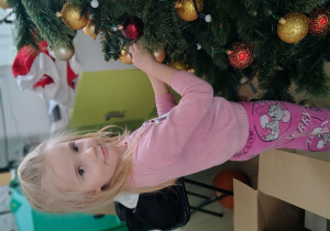 Dziewczynka ubiera choinkę.