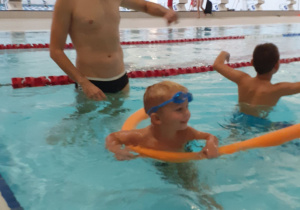 Dzieci pływają w basenie pod kierunkiem instruktora