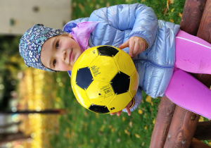 Dziewczynka trzyma piłkę.