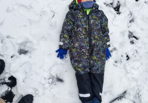 Chłopiec leży na śniegu.