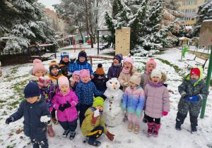 Dzieci pozują przy ulepionym bałwanku.