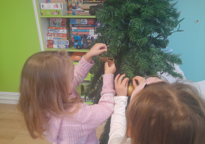 Dziewczynki ubierają choinkę.