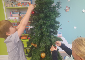Dzieci ubierają choinkę.