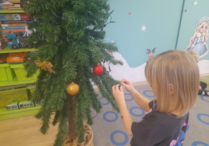 Dziewczynka ubiera choinkę.