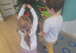 Dzieci ubierają choinkę.