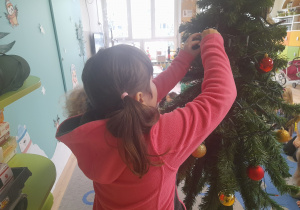 Dziewczynka ubiera choinkę.