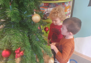 Chłopcy ubierają choinkę.