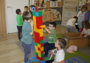 Dzieci budują rakietę z klocków.