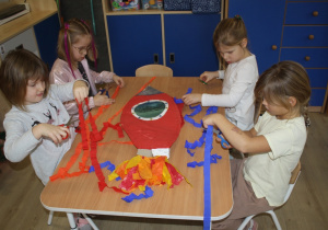 Dzieci tworzą rakietę z bibuły.