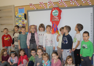 Dzieci prezentują rakietę wykonaną z bibuły.