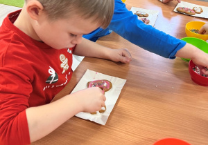 Dziecko dekoruje pierniczek.