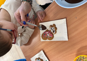 Dziecko dekoruje pierniczek.