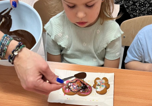 Dziecko dekoruje pierniczek.