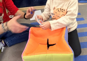 Dziewczynka wyjmuje z pudełka zagadkę od Teo.