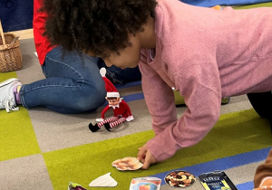 Dziewczynka układa na dywanie obrazki na literę "b".