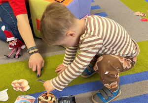 Chłopiec dokłada na dywan obrazek na literę "b".