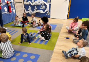 Dzieci siedzą na dywanie.