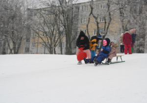 Dzieci zjeżdżają z górki.