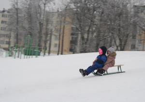 Dzieci zjeżdżają z górki.