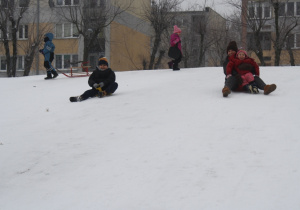 Dzieci zjeżdżają z górki.