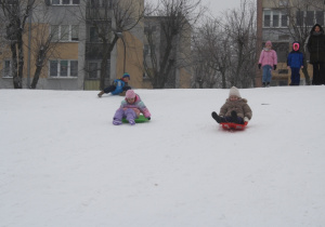 Dzieci zjeżdżają z górki.