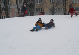 Dzieci zjeżdżają z górki.