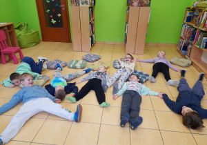 Dzieci naśladują wykonywanie aniołka na śniegu.