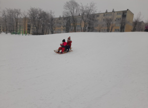 Dzieci zjeżdżają z górki na sankach