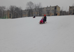 Dziecko zjezdża na sankach.