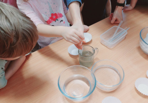 Dzieci wykonują eksperyment z lodem.