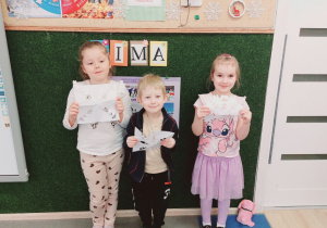 Dzieci stoją z wycinankami.