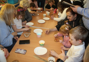 Dzieci dekorują pierniki z dziadkami i babciami.