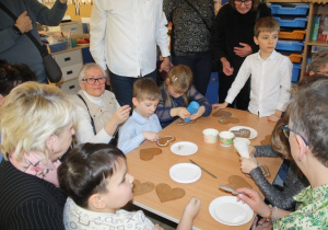 Dzieci dekorują pierniki z dziadkami i babciami.