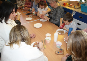 Dzieci dekorują pierniki z dziadkami i babciami.
