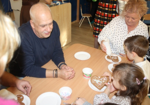 Dzieci dekorują pierniki z dziadkami i babciami.