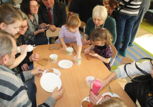 Dzieci dekorują pierniki z dziadkami i babciami.