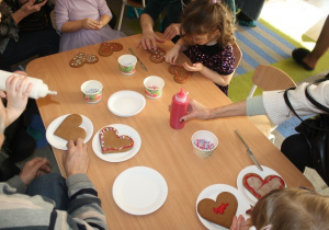 Dzieci dekorują pierniki z dziadkami i babciami.