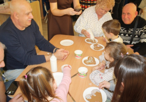 Dzieci dekorują pierniki z dziadkami i babciami.