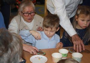 Dzieci dekorują pierniki z dziadkami i babciami.