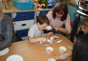 Dzieci dekorują pierniki z dziadkami i babciami.