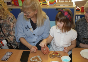 Dzieci dekorują pierniki z dziadkami i babciami.