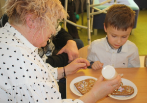 Dzieci dekorują pierniki z dziadkami i babciami.